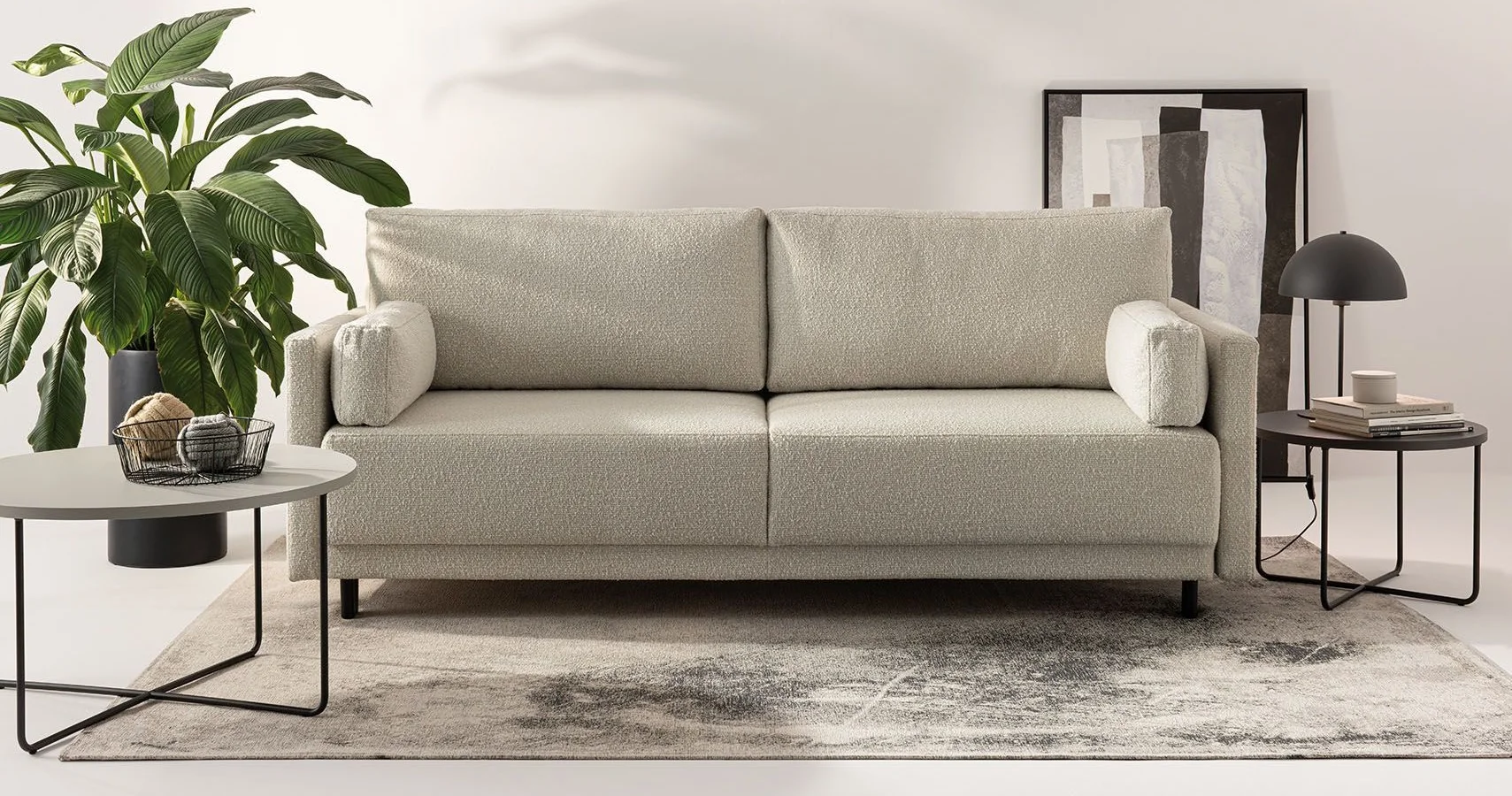 Sofa z tkaniny boucle na dekoracyjnym dywanie z subtelnym wzorem.